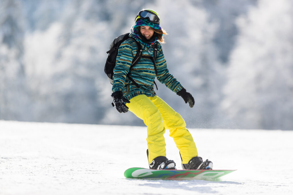 Junge Snowboarderin fährt einen Hang hinunter