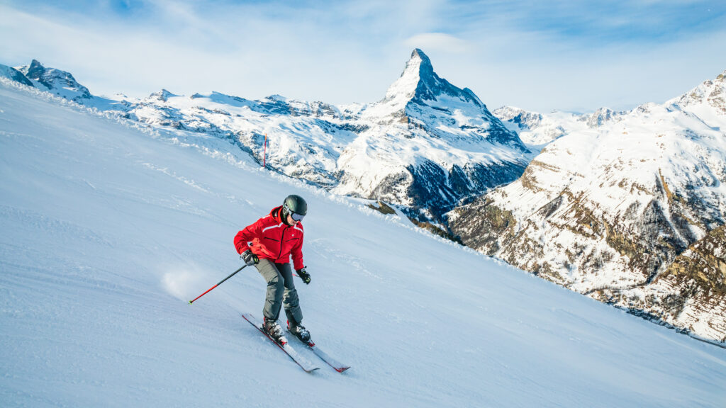 Skifahrer bei der Abfahrt, im Hintergrund die Berge