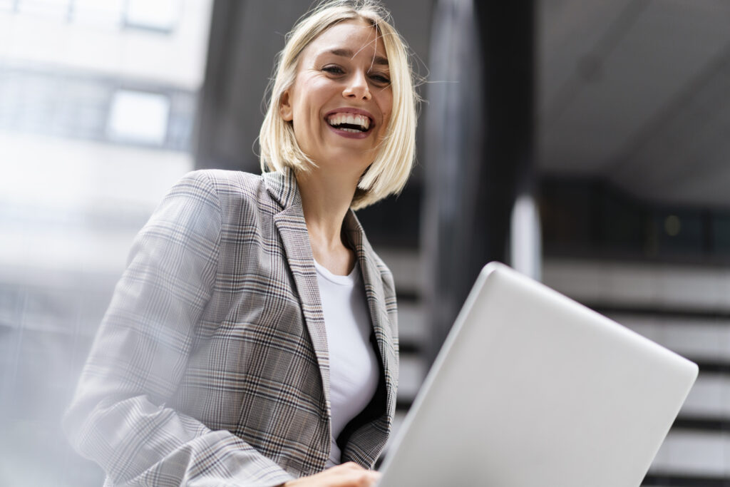 Porträt einer fröhlichen jungen Geschäftsfrau mit Laptop