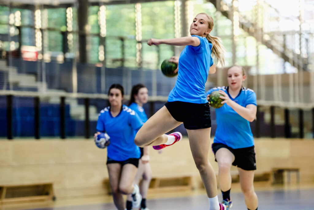 Handballspielerin wirft im Sprung den Ball beim Training in der Halle