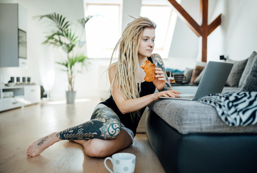 young woman with laptop sitting on floor at home checking emails, Cyberkriminalität