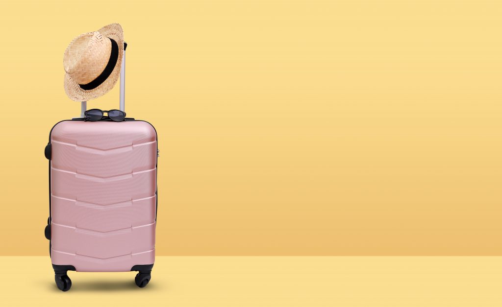 Koffer und Sonnenhut für die Reiseplanung ohne Kinder 