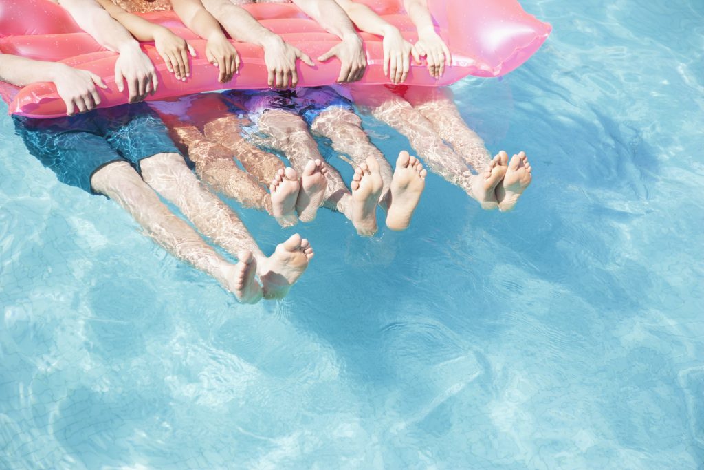 Schwimmbecken mit den Beinen von Schwimmern, die sich an einer Luftmatratze festhalten