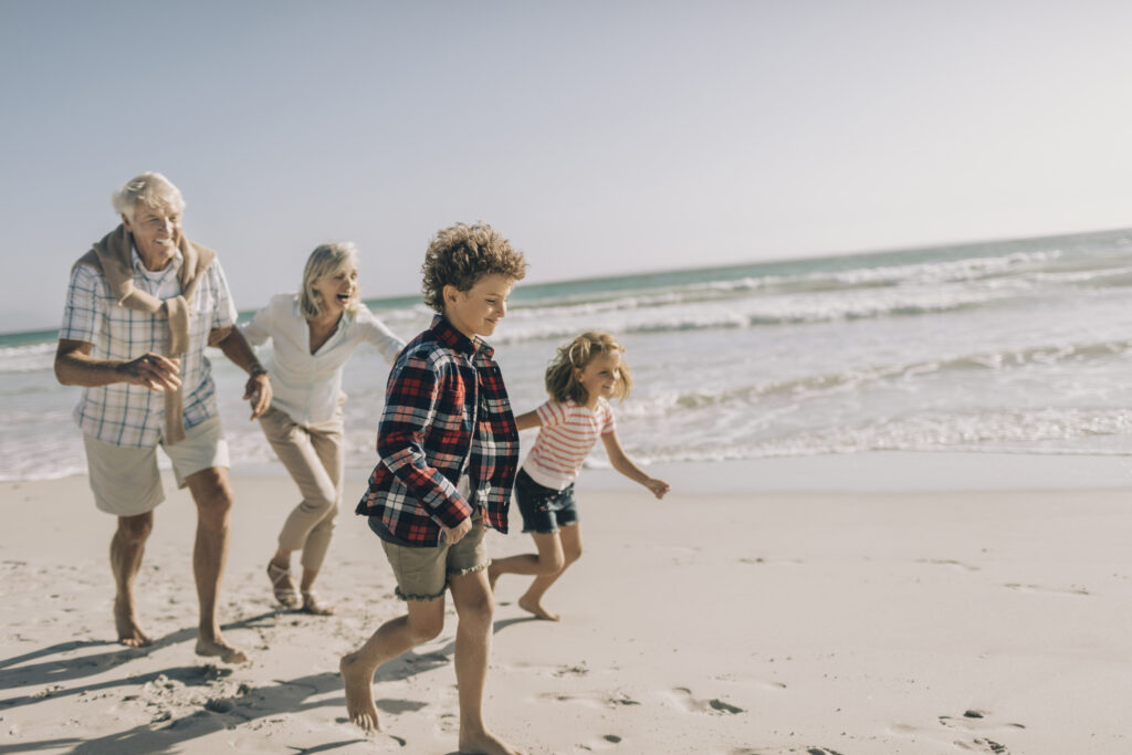 Großeltern und deren Enkelkinder laufen am Strand