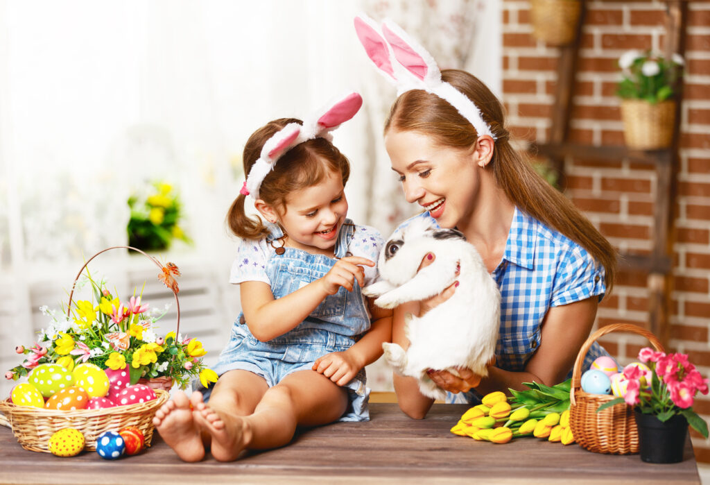 Mutter mit Mädchen mit einem Hasen und Osterschmuck