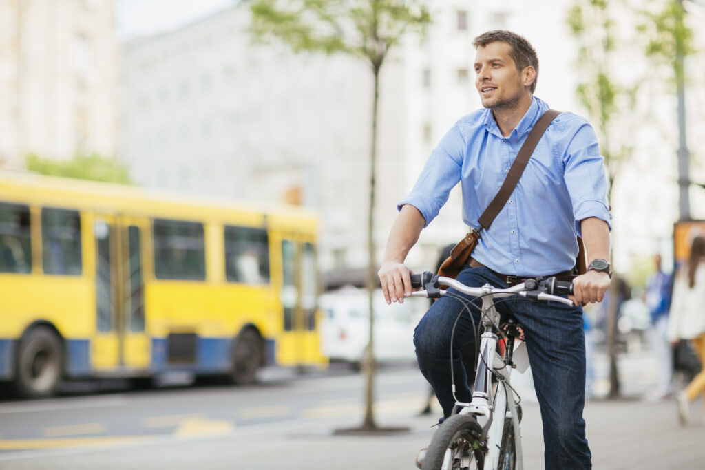 Mann auf einem Fahrrad mit Straßenverkehr im Hintergrund