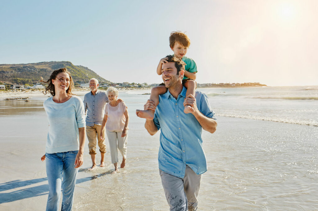 Familie mit drei Generationen macht einen Spaziergang am Strand.